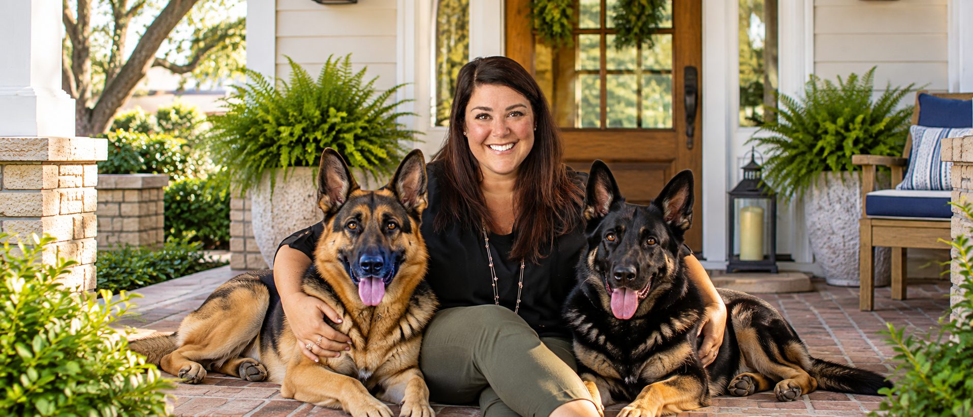 Jill Wood, Emerald Coast REALTOR® with ERA American Real Estate, relaxing on a front porch with her two German Shepherds.